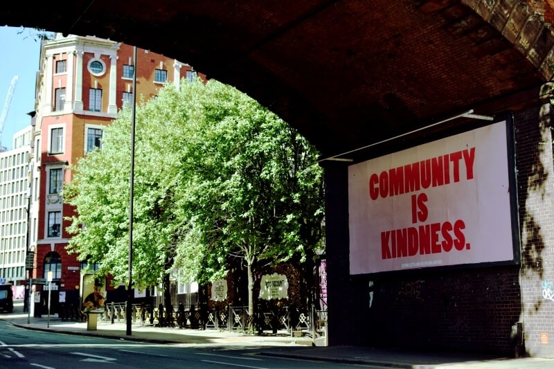 Banner under a bridge stating 'Community is kindness'
